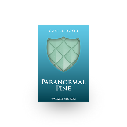 Front packaging of Castle Door Paranormal Pine wax melt, featuring pale green dragonscale wax visible through a shield-shaped window.