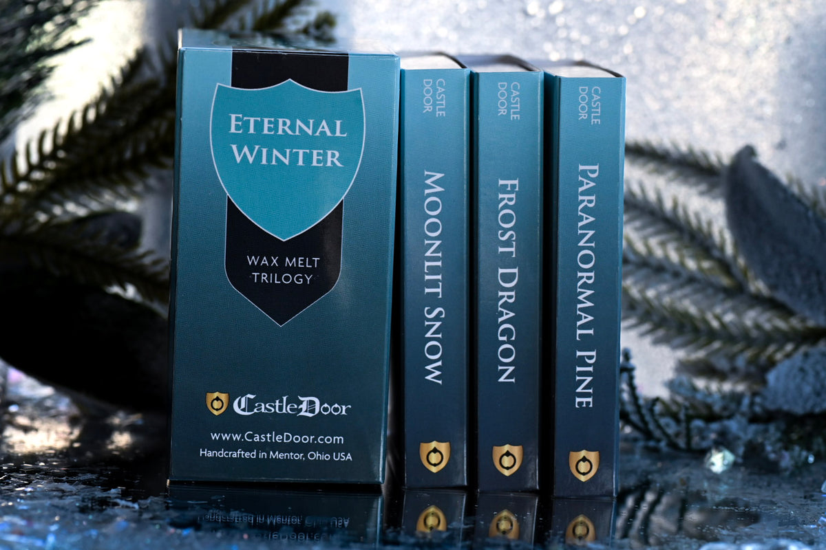 Eternal Winter Wax Melt Trilogy collector's box displayed beside the Moonlit Snow, Frost Dragon, and Paranormal Pine scent boxes in a snowy setting.